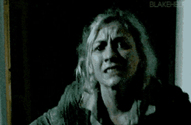 a woman is making a funny face in a dark room in a black and white photo .