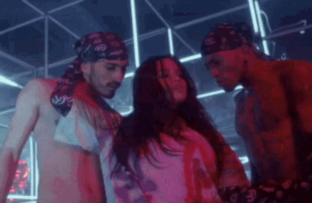 two men and a woman are dancing in a dark room .
