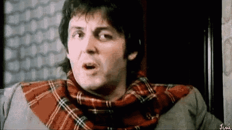 a man is wearing a plaid scarf around his neck and making a funny face .