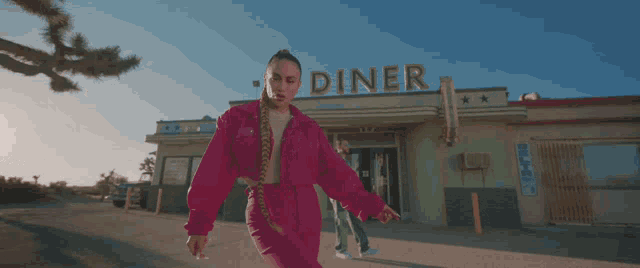 a woman in a pink outfit stands in front of the diner