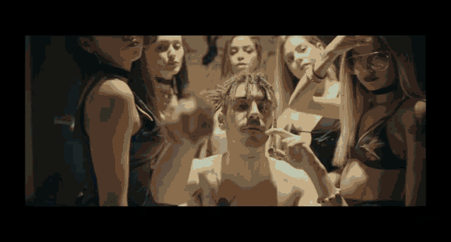 a group of women are standing around a man in a bikini