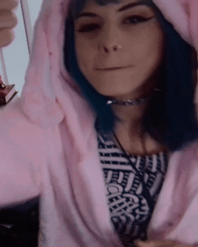a girl with blue hair is wearing a pink hoodie and a choker