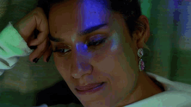 a close up of a woman 's face with a blue light shining on it
