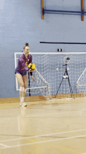 a girl in a purple jersey with the number 6 on it throws a volleyball