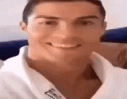 a close up of a man 's face with a white shirt on smiling .