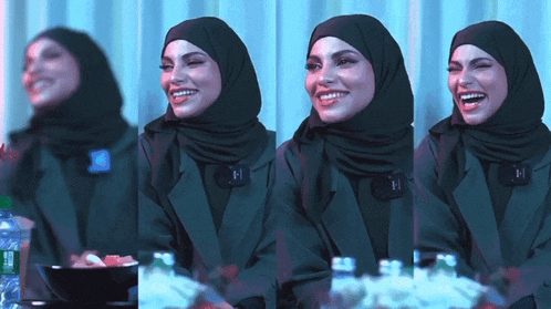a woman wearing a hijab and a green jacket is smiling and laughing