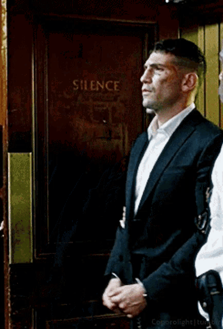 a man in a suit and white shirt is being escorted by two police officers .