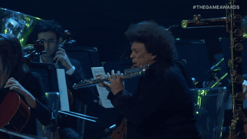 a man playing a flute in front of an orchestra with #thegameawards on the bottom right