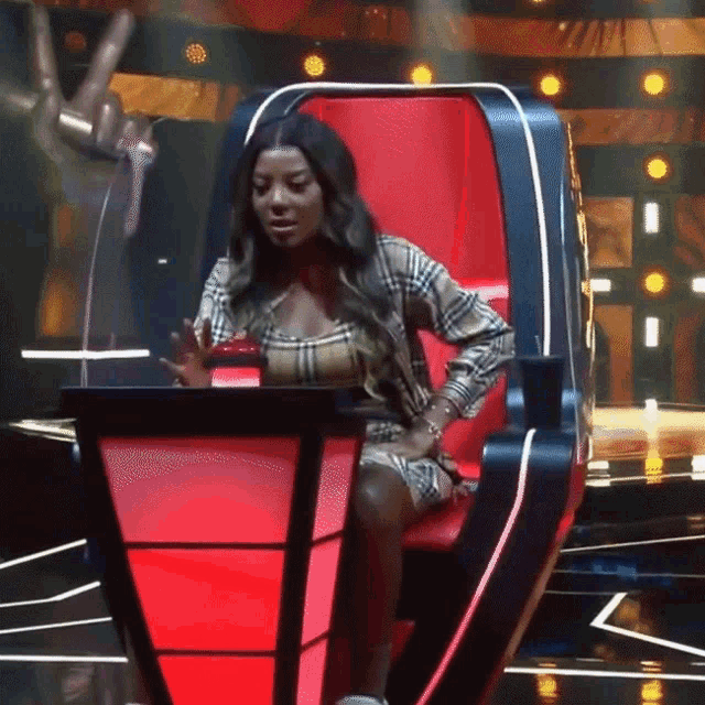 a woman in a plaid shirt sits in a red chair