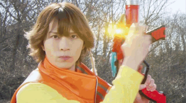 a young man in a yellow shirt is holding a red and yellow toy gun
