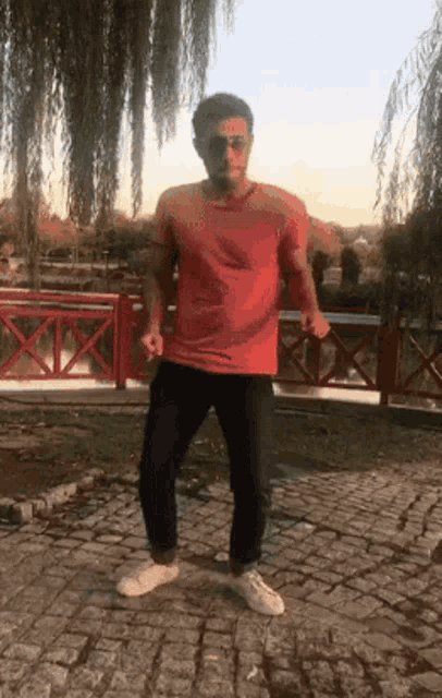 a man in a red shirt and black pants is dancing