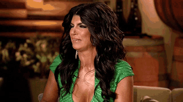 a woman with long dark hair is wearing a green dress