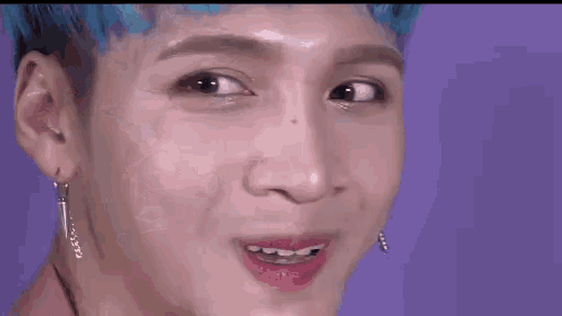 a close up of a person 's face with blue hair making a funny face .