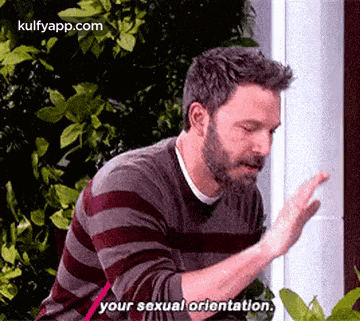 a man with a beard is talking about his sexual orientation while standing in front of a building .