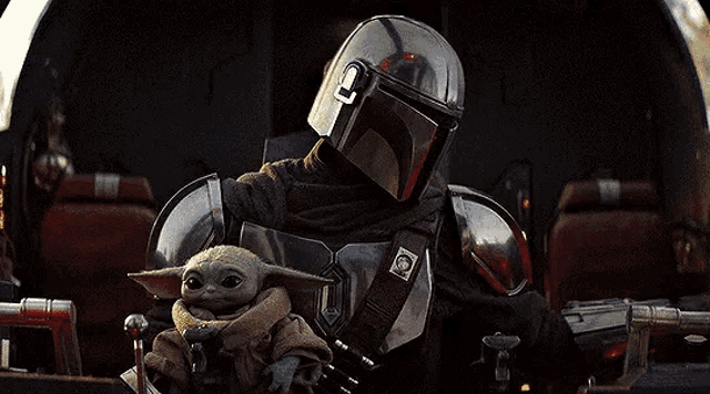 a man in a helmet is holding a baby yoda in a helicopter .
