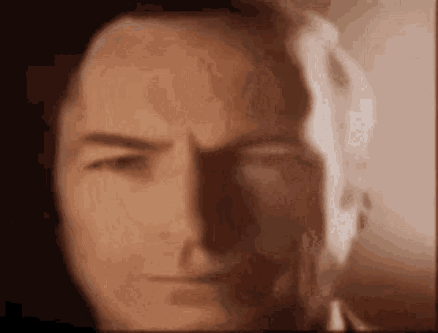 a close up of a man 's face with a reflection of another man .