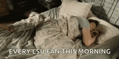 a woman is sleeping in a bed with the words `` every lsu fan this morning '' written on the bottom .
