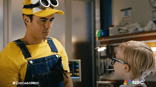 a man in overalls and a hat talks to a little boy with the hashtag #chicagomed on the bottom