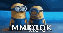 two minions wearing goggles are standing next to each other with the words mmkqqk written on the bottom .