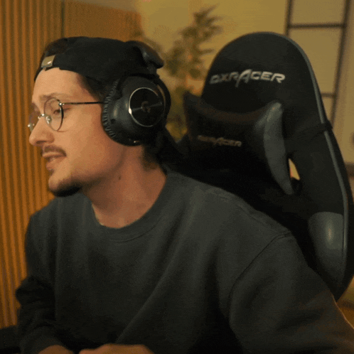 a man wearing headphones is sitting in a dxracer gaming chair