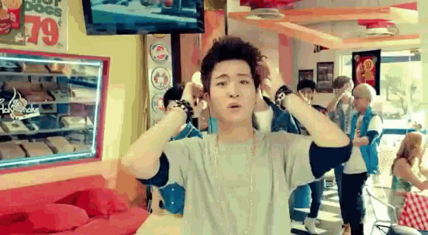 a young man is standing in a diner holding his hair .