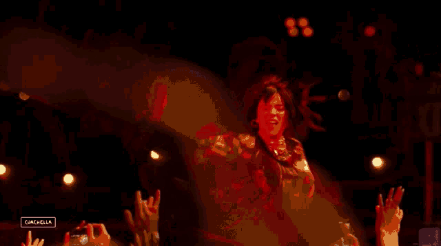 a woman singing into a microphone in front of a crowd with a sign that says cancella on it