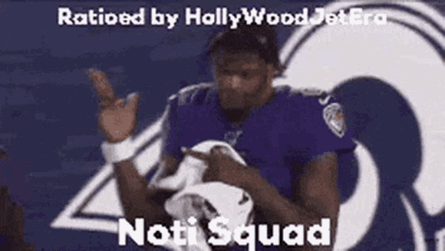 a football player in a purple jersey is holding a towel and pointing at something .