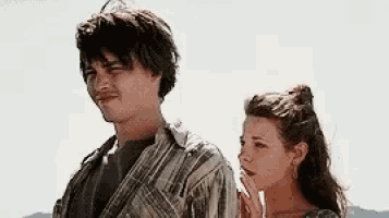 a man and a woman are standing next to each other in front of a blue sky .