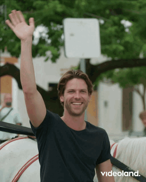 a man riding a horse drawn carriage waves his hand