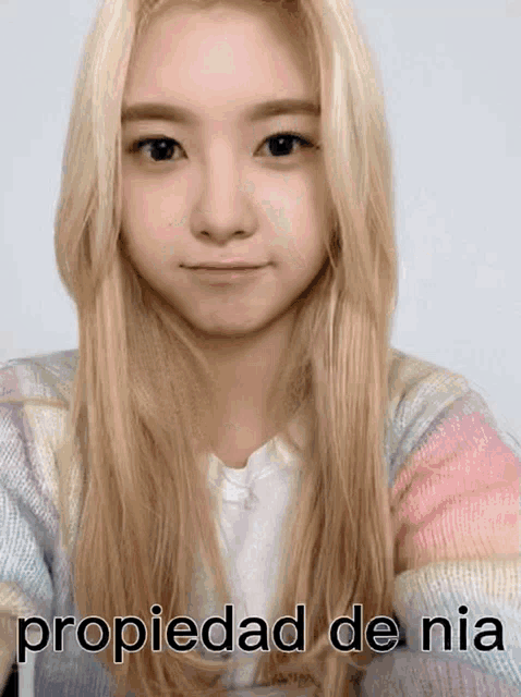 a girl with long blonde hair is wearing a sweater that says propiedad de nia on it