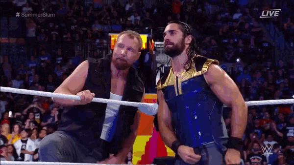 a couple of men are standing in a wrestling ring talking to each other .
