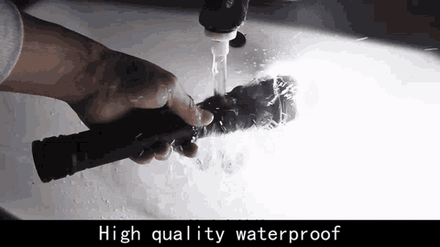 a person is washing a flashlight in a sink with the words high quality waterproof on the bottom