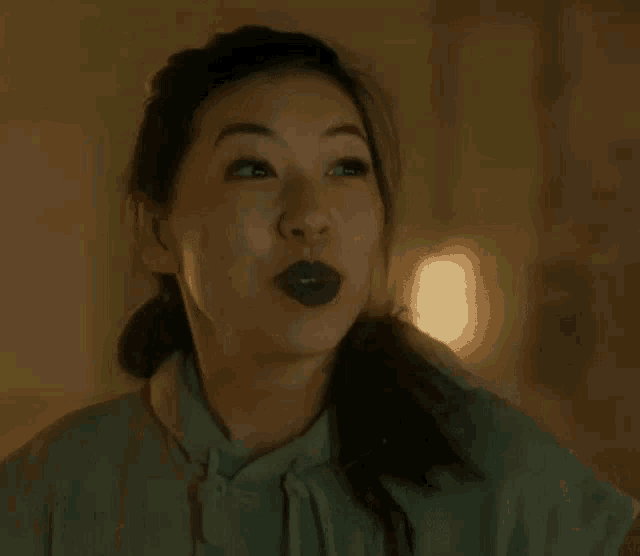 a close up of a woman wearing purple lipstick and a ponytail .