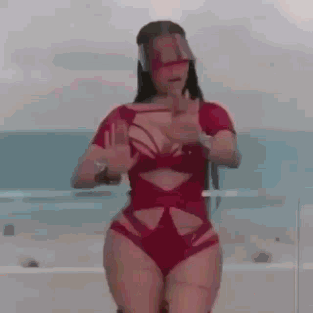 a woman in a red swimsuit and sunglasses is standing on a boat .