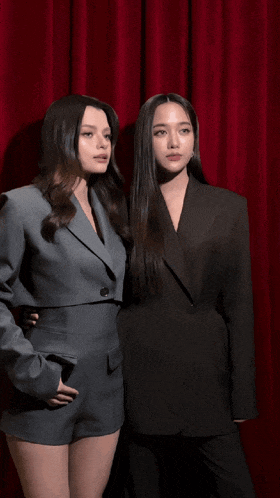 two women standing next to each other wearing suits and shorts