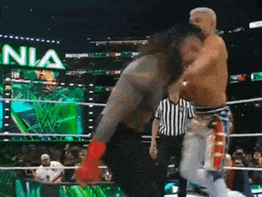 two men are wrestling in a ring with a referee and the word nia in the background