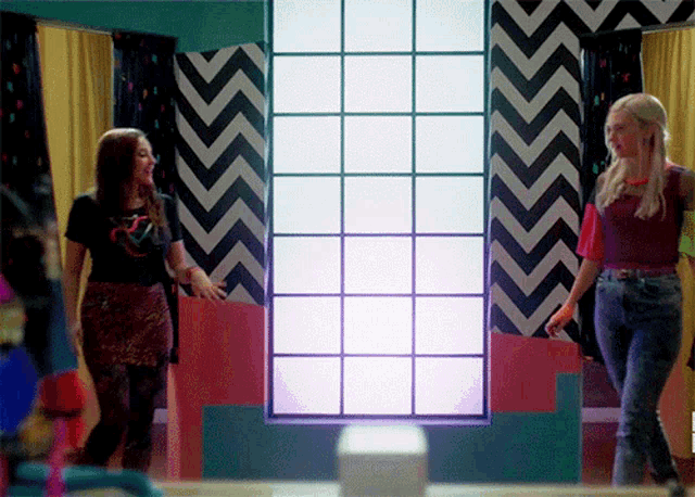 two women are standing in front of a window with a purple light coming out of it
