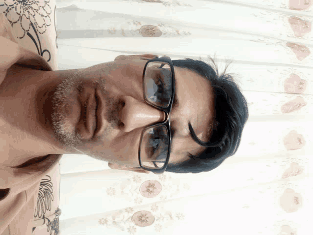 a man with glasses and a tattoo on his arm looks down at the camera