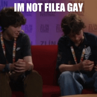two men sitting on a red couch with the words im not filea gay written above them
