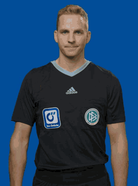 a man wearing a black adidas shirt gives a thumbs up