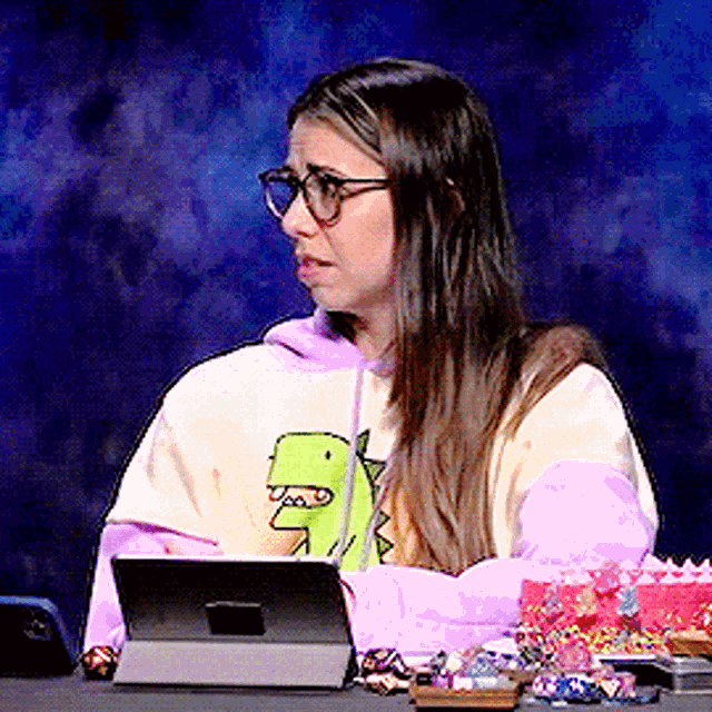 a woman wearing glasses and a hoodie with a dinosaur on it