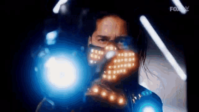 a man wearing a mask with lights on it is standing in front of a light .