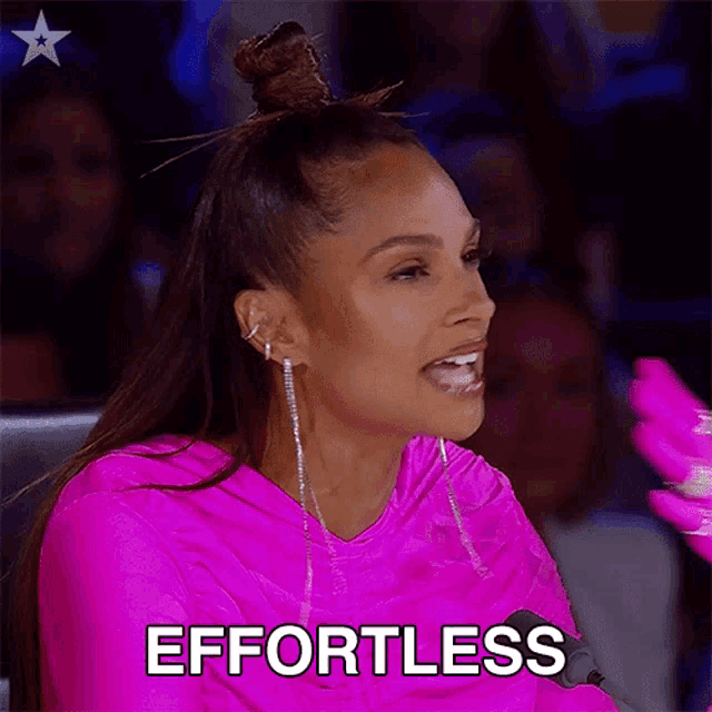 a woman in a pink dress is sitting in front of a microphone and says effortless