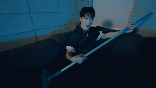 a man in a black shirt is sitting on a couch holding a pole