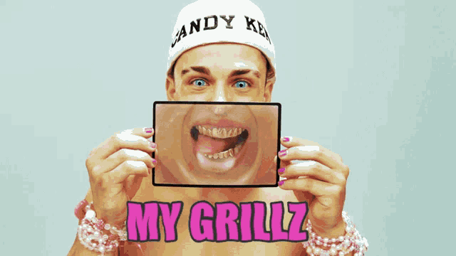 a shirtless man is holding up a picture of his face with the words my grillz written below it