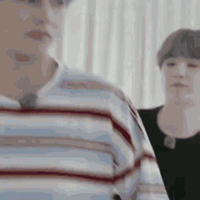 a man in a striped shirt is standing next to another man in a black shirt .