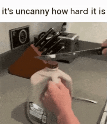a person is cutting a bottle of milk with a knife in a kitchen .