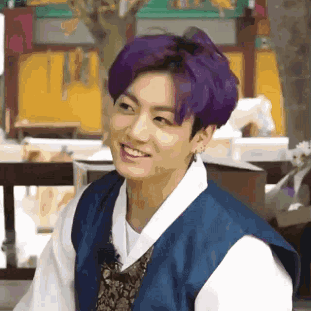a young man with purple hair is wearing a blue and white kimono and smiling .