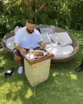 a man is sitting on a couch with a tray of food on it .