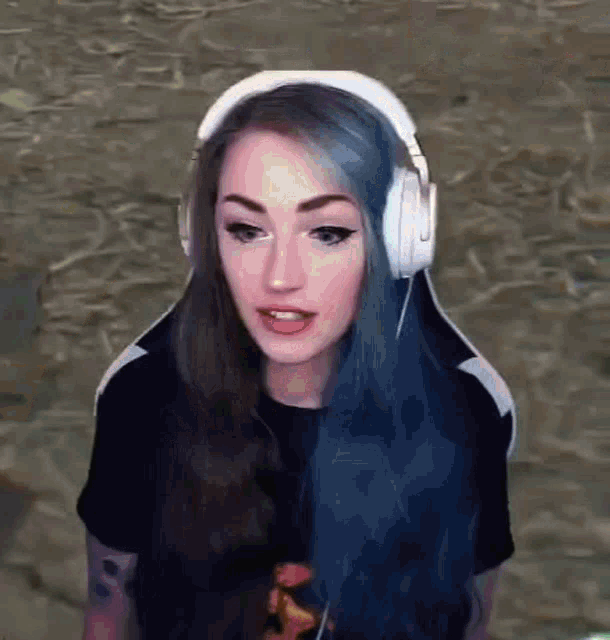 a girl with blue hair is wearing headphones and a black shirt .